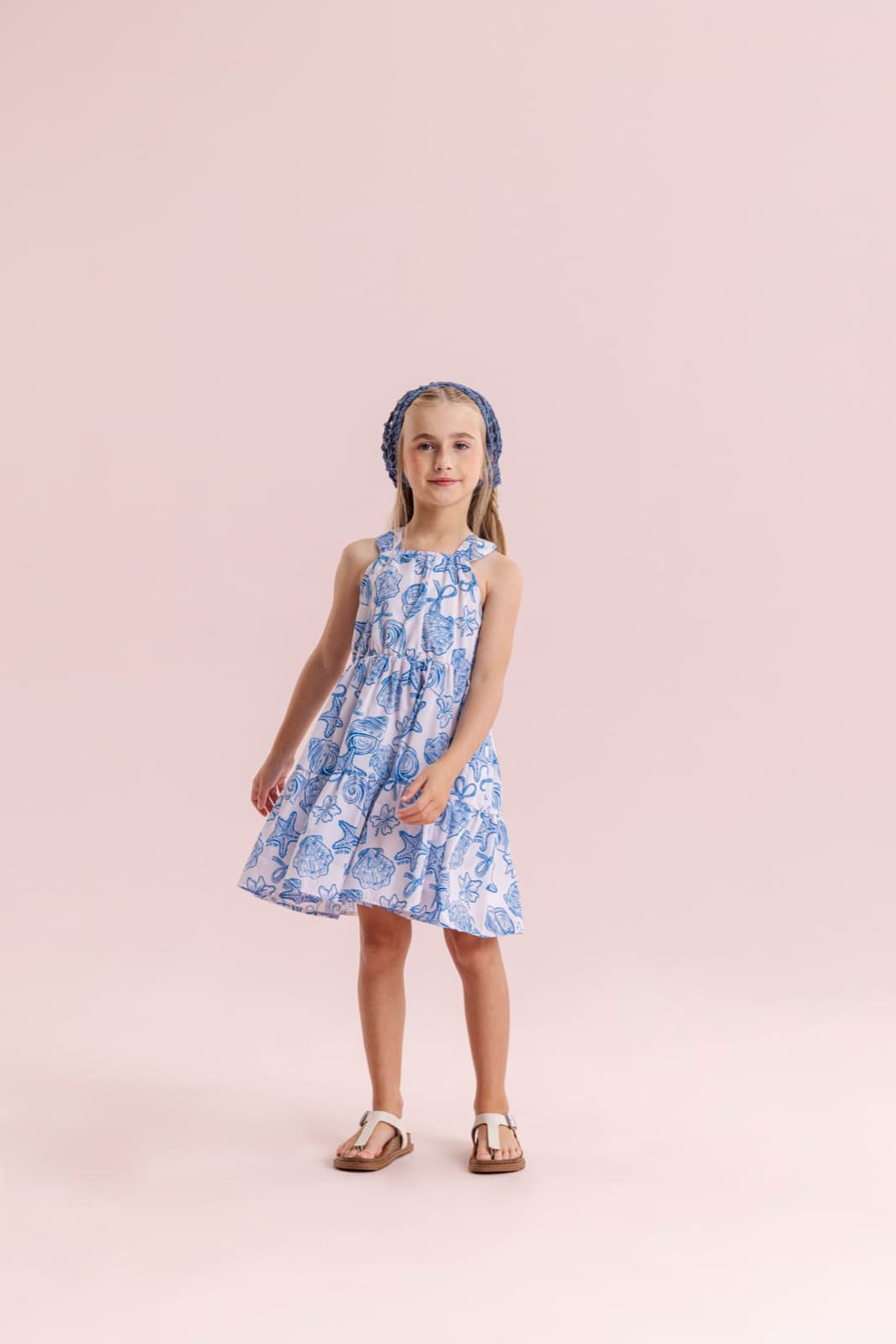 Menina usando vestido azul e branco com estampa marítima