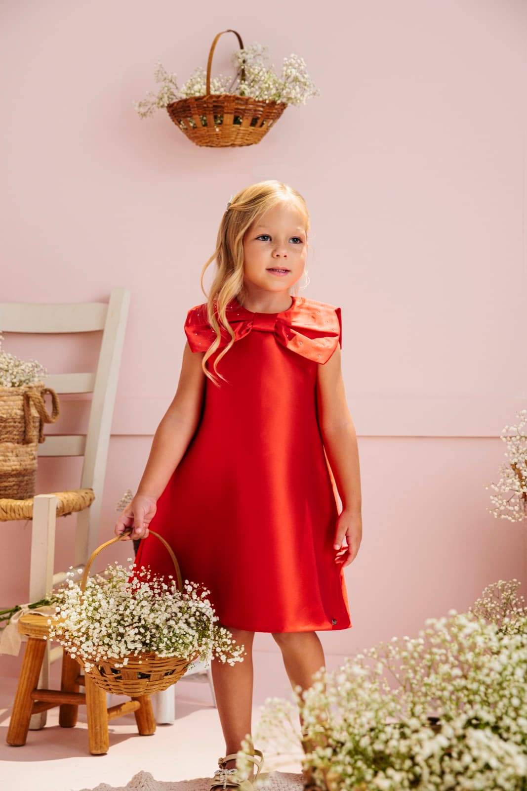 Menina usando vestido vermelho com laço entre flores brancas